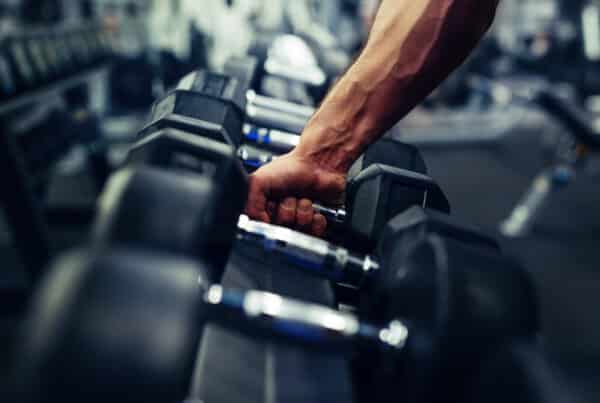 Person picking up a dumbbell from a rack at the gym