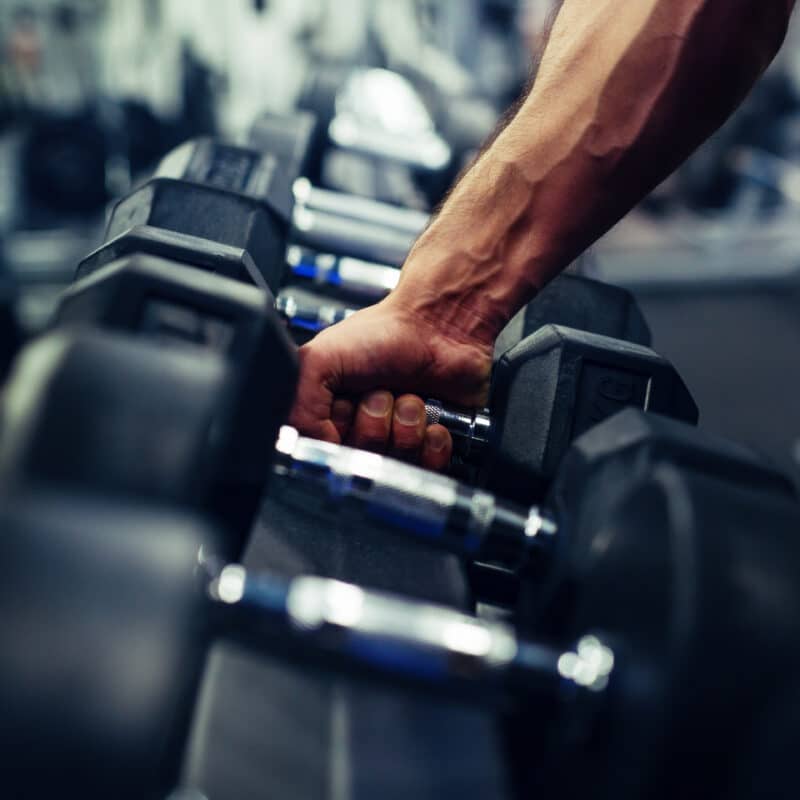 Person picking up a dumbbell from a rack at the gym
